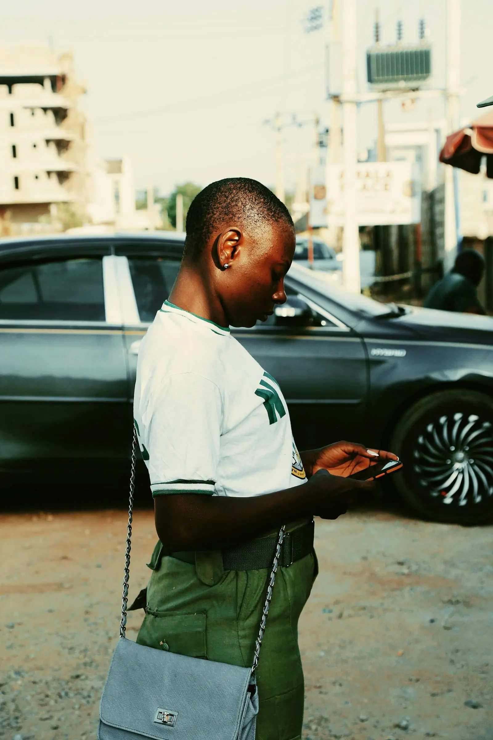 A young woman looking at her phone outdoors in Abuja