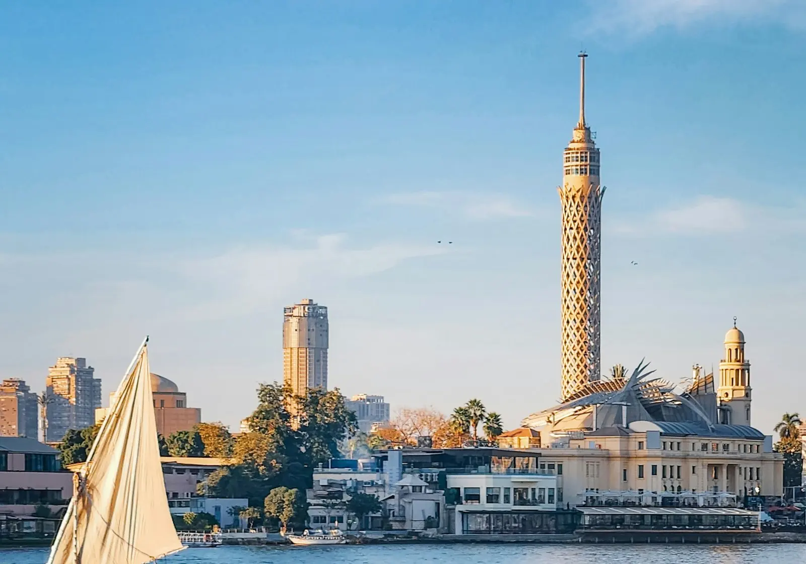 A felucca sails on the Nile in Cairo with the Cairo Tower behind it