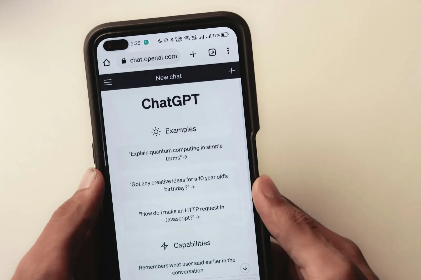 Two hands holding a smartphone with the ChatGPT chat screen open