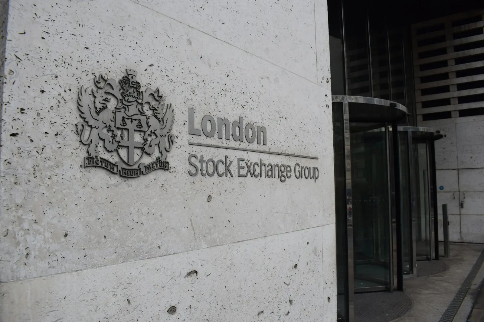 The London Stock Exchange Group crest and name carved into a stone wall beside revolving doors