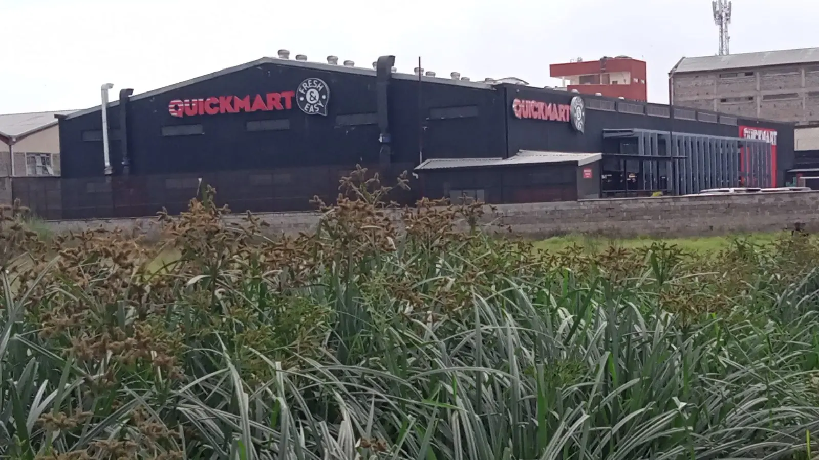 A Quickmart supermarket building with red Quickmart signs on a black facade in Kenya