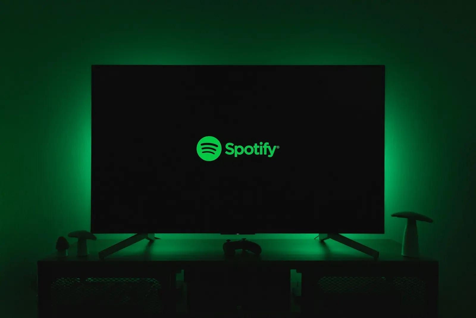 The green Spotify logo on a television screen glowing in a dark room